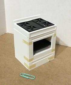 a white stove with two burners sitting on the floor next to a paper clip