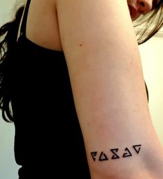 a woman with a tattoo on her arm that has three letters written in the middle