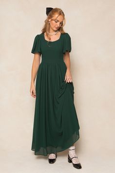 Twirl in style with the Abbie Dress in Emerald Chiffon. The flowy chiffon fabric and subtle sweetheart neckline provide a romantic touch, while the short bell sleeves and maxi-length skirt with functional pockets add a playful twist. This dress is not only the ultimate fall bridesmaids silhouette, but perfect for date night, special events, church and more. With a hidden back zipper, princess seams on the bodice and full lining, you simply can't go wrong. This women's dress is available in up to Dark Green Modest Dress, Formal Winter Wedding Guest Dress Classy, Lotr Bridesmaid Dresses, Modest Christmas Dresses, Green Dresses For Wedding, Eucalyptus Dress, Dark Green Formal Dress, Modest Dresses For Church, Green Wedding Party