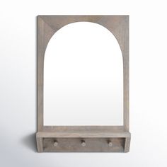 an arched wooden mirror on a white wall