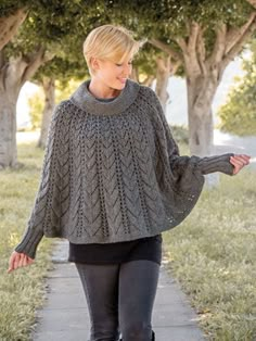 a woman walking down a sidewalk wearing a gray sweater