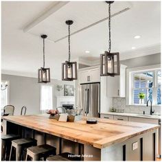 a kitchen island with stools and lights hanging from it