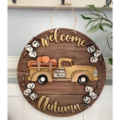 a wooden sign that says welcome autumn with a truck and pumpkins on the back