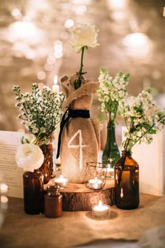 a table topped with bottles filled with flowers and candles