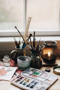 an instagram page with photos and candles on the table next to it, which is also containing pens and pencils