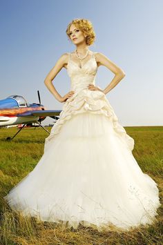 a woman in a white dress standing next to an airplane