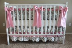 a white crib with pink bows and polka dots on the bedding is shown