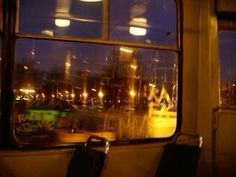 an empty seat in front of a window with the city lights seen through it at night