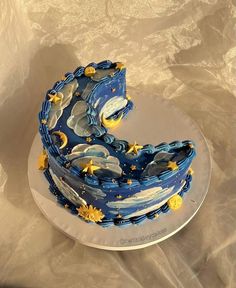 a blue cake with stars and moon designs on it's sides is sitting on a plate