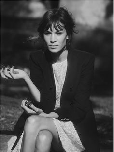 black and white photograph of a woman sitting on the ground with her hand in her pocket