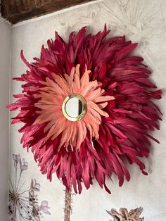 a large red flower sitting on top of a wooden table next to a mirror and vase