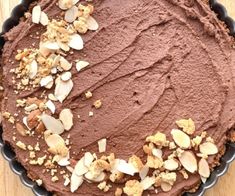 a chocolate pie topped with nuts on top of a wooden table