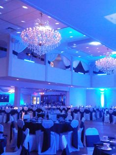 an empty banquet room with chandeliers and tables set up for formal function in blue lighting