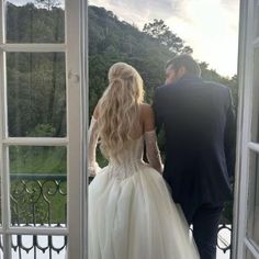 a bride and groom are looking out an open window at the view from their balcony