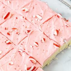 a piece of cake with pink frosting and nuts on top, sitting on a table