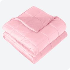 a pink comforter is folded up on top of a white bed sheet and pillow