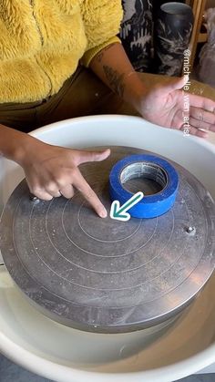 a person pointing at a piece of tape in a bowl with other items around it