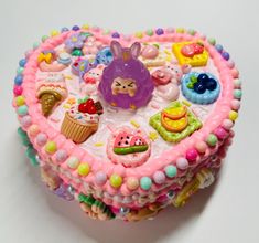 a heart shaped cake decorated with various candies and other decorations on top of it