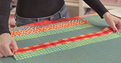 a woman is cutting up some fabric on a piece of paper that has been cut into strips