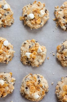 cookies with white chocolate chips and marshmallows are arranged on a baking sheet