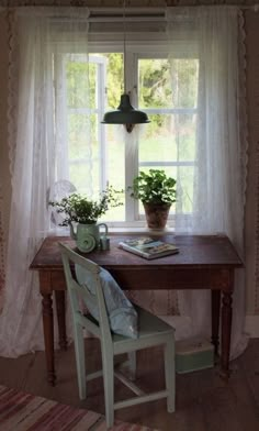 a wooden table sitting in front of a window next to a chair and potted plant