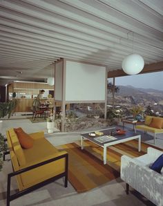 a living room filled with furniture and a large window overlooking the mountains in the distance