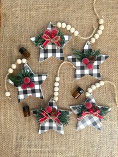 four christmas decorations are hanging on a burlap background with beads and holly berries