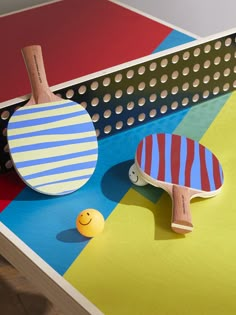 two ping pong paddles sitting on top of a colorful table