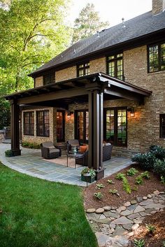 an outdoor living area with patio furniture and stone pavers flooring in front of a brick house