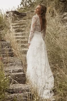 a woman in a long white dress standing on some steps with her back to the camera