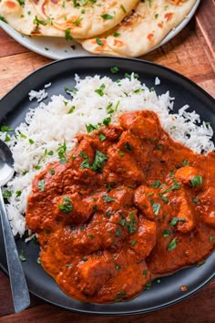 two plates filled with rice and meat on top of a wooden table next to naan bread