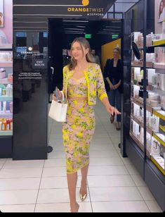 a woman in a yellow dress is walking down the aisle with her hand on her hip