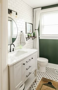 a white bathroom with green walls and black and white tile flooring on the wall