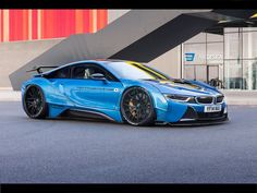 a blue bmw sports car parked in front of a building with an orange stripe on the side