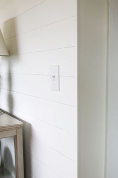 a room with white walls and a lamp on the side table in front of it