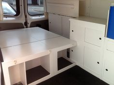 the interior of a van with white furniture and cabinets in it's back area