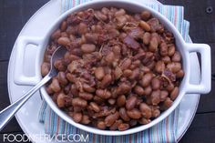 a white bowl filled with beans sitting on top of a table next to a fork