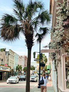 a woman is walking down the street with her hand in her pocket and palm trees