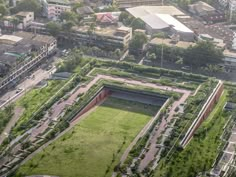 an aerial view of a city with lots of green grass and buildings in the background