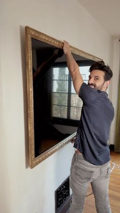 a man standing in front of a flat screen tv with his hands on the frame