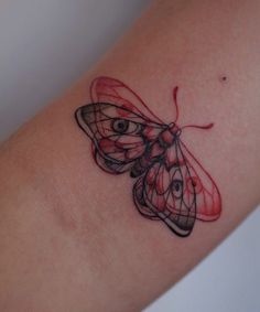 a small butterfly tattoo on the arm with red and black lines coming out of it's wings