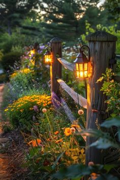 a wooden fence with two lights on it in the middle of some flowers and trees