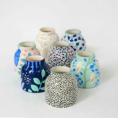 a group of vases sitting next to each other on a white surface with blue and green designs