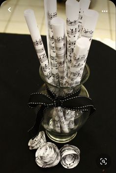 a glass vase filled with lots of white paper music notes on top of a table