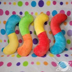 three different colored stuffed animals sitting next to each other on a polka dot covered surface