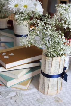 several books are stacked on top of each other with daisies in the vases