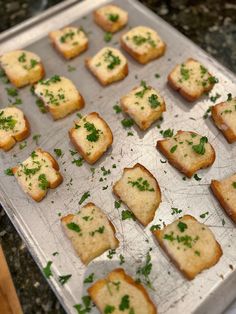 small pieces of bread with parsley on top sitting on a baking sheet, ready to go into the oven