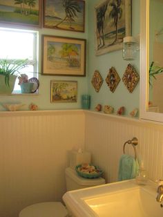 a bathroom with blue walls and pictures on the wall above the toilet, along with a white sink