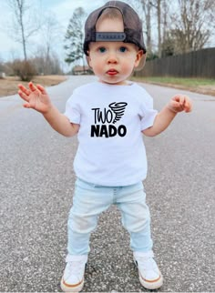 a little boy standing on the street with his hands in the air and wearing a t - shirt that says taco naddo