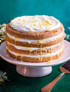 a frosted cake sitting on top of a white plate next to a lit candle